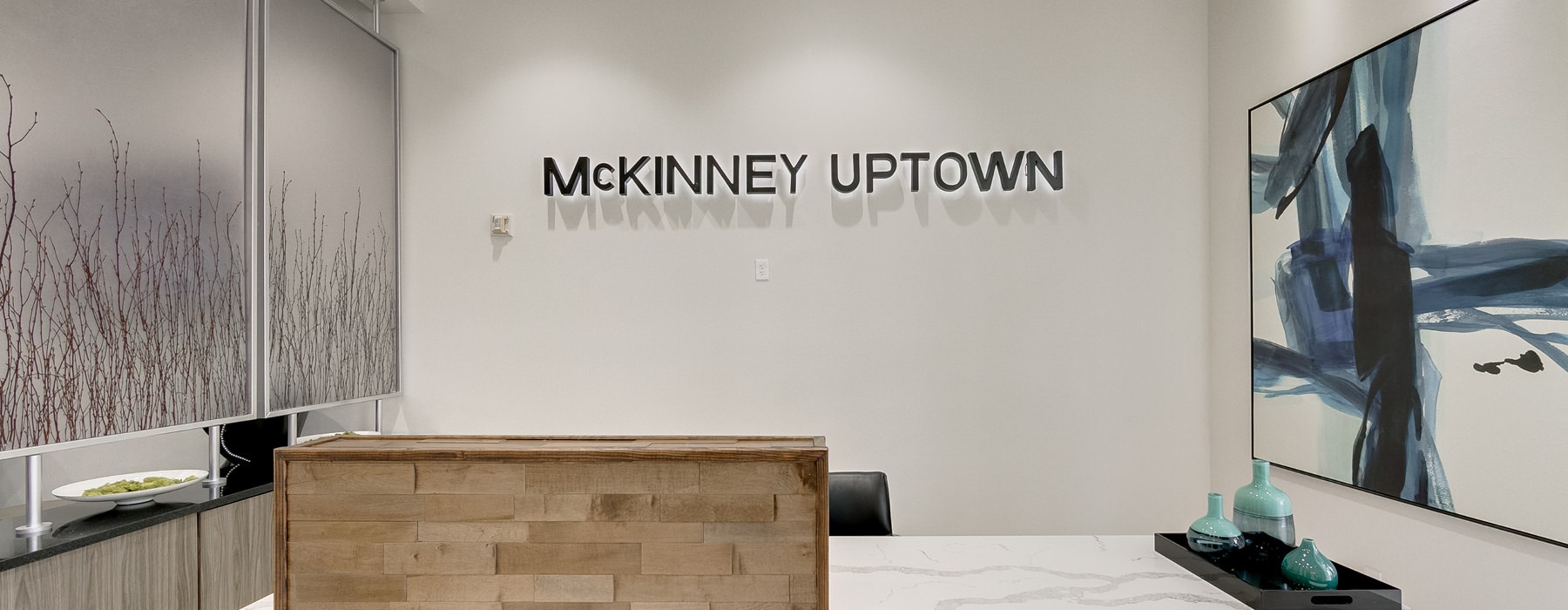 McKinney Uptown sign, mounted on wall above concierge area in lobby